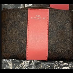 Signature Print Coach Wristlet with Coral Stripe.